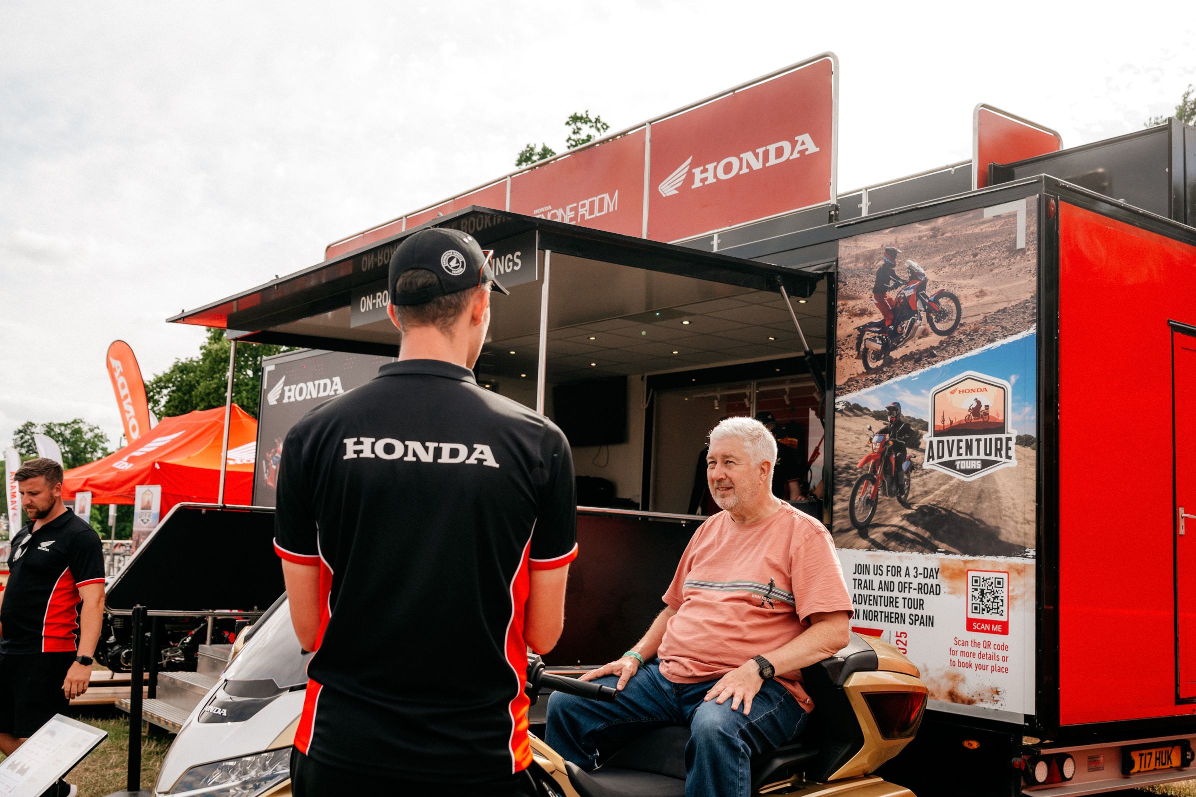 Two individuals in discussion near Honda stall.
